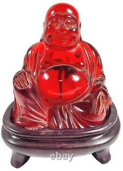 Bouddha rouge en ambre souriant/riant avec support. Environ 3-11/16 H x 3 1/2 L.