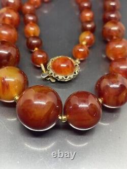 Collier de perles anciennes en bakélite cerise ambrée, 23 perles graduées, vendu en l'état.