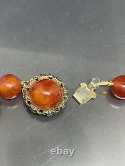 Collier de perles anciennes en bakélite cerise ambrée, 23 perles graduées, vendu en l'état.
