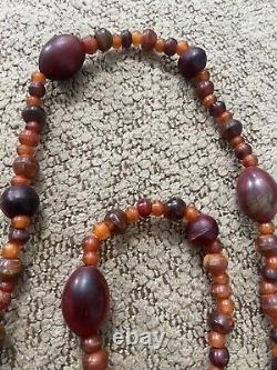 Collier de perles d'ambre antique vintage rouge et orange. Brille sous UV